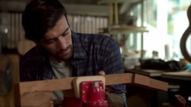 Yetenekli bir Luthier atölyesinde bir akustik gitarın vücudunu zımparalamak için çok çalışıyor. Detaylara dikkat etmek Luthier 'in elleri ve gitarının yakın görüntüsünde açıkça görülüyor..