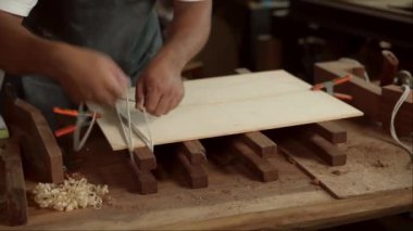 Yetenekli bir Luthier atölyesinde bir akustik gitarın vücudunu zımparalamak için çok çalışıyor. Detaylara dikkat etmek Luthier 'in elleri ve gitarının yakın görüntüsünde açıkça görülüyor..