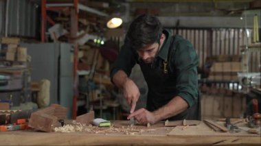 Yetenekli bir Luthier atölyesinde bir akustik gitarın vücudunu zımparalamak için çok çalışıyor. Detaylara dikkat etmek Luthier 'in elleri ve gitarının yakın görüntüsünde açıkça görülüyor..