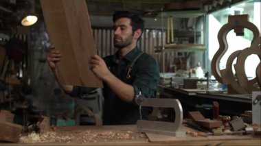 Yetenekli bir Luthier atölyesinde bir akustik gitarın vücudunu zımparalamak için çok çalışıyor. Detaylara dikkat etmek Luthier 'in elleri ve gitarının yakın görüntüsünde açıkça görülüyor..