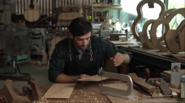 Yetenekli bir Luthier atölyesinde bir akustik gitarın vücudunu zımparalamak için çok çalışıyor. Detaylara dikkat etmek Luthier 'in elleri ve gitarının yakın görüntüsünde açıkça görülüyor..