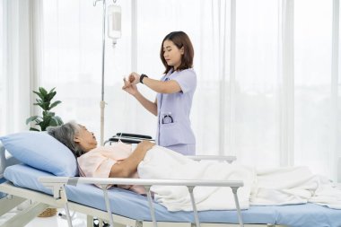 Yaşlı bir hastanın bakıcısı ya da hemşiresi, saptanan tıbbi duruma göre hastaya verilen normal salin oranını ayarlar. Hastanedeki hastalarla hemşire ilgileniyor..