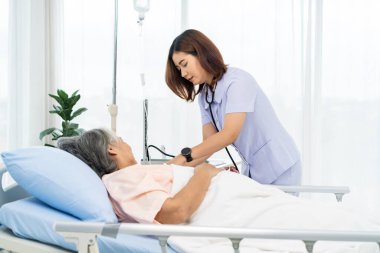 Günlük teftiş. Yaşlı bir hastanın bakıcısı ya da hemşiresi hastanın kan basıncını ve kalp atışını ölçmeye hazırlanıyor. Hastanelerde ya da kliniklerde hastalara hemşireler bakar.