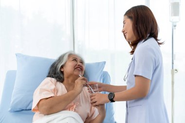 Yaşlı Asyalı hasta iyileşme sürecinde hastaneye yattı, hemşire ona baktı ve susadığında ona su verdi. Hastanelerde ya da kliniklerde hastalara hemşireler bakar.