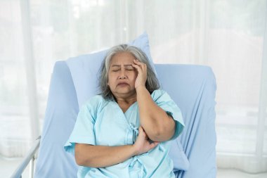 Hastaneye kaldırılan yaşlı bir kadın hasta acı içinde başını hastane yatağında tutuyordu. Beyin kanamasından kaynaklanan akut ağrı (felç). Tıbbi ve sağlık hizmetleri kavramı