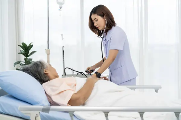 Daily inspection A nurse or caregiver of an elderly patient measures the patient\'s blood pressure and heart rate. Nurses care for patients in hospitals or clinics.