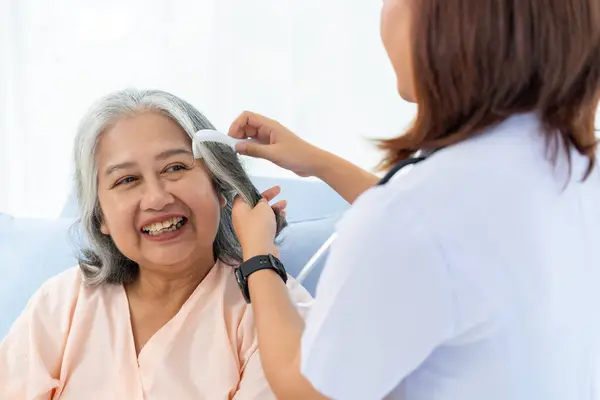 Close-up photo of an elderly Asian patient admitted to the hospital. The nurse gives a pep talk and combs the patient\'s hair. A nurse takes care of patients in a hospital or clinic.
