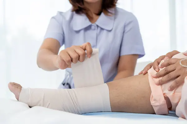 Close-up photo of an Elderly Asian patient admitted to hospital A nurse cares for a patient\'s injured leg bandage. A nurse takes care of patients in a hospital or clinic.