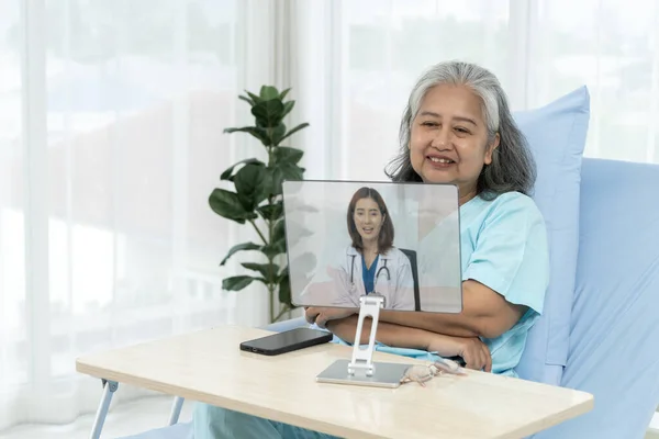 Elderly Asian patient admitted to hospital Doctors give advice about their patients medical conditions via the internet. Patients use video conferencing with their general practitioner via computer