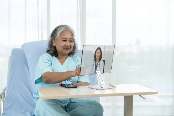 Elderly Asian patient admitted to hospital Doctors give advice about their patients medical conditions via the internet. Patients use video conferencing with their general practitioner via computer