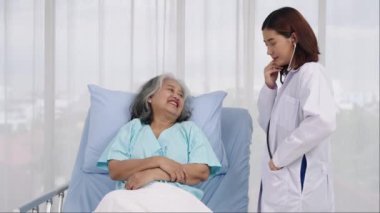 Orta boy, yaşlı bir Asyalı kadın hasta göğüs hastalığından hastaneye kaldırıldı. Kadın doktor akciğer solunumunu kontrol etmek için stetoskop kullanıyor. Tıbbi ve sağlık hizmetleri kavramı