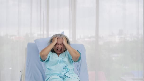 一位住在医院的老年女性病人痛苦地把头靠在病床上 脑出血 引起的急性疼痛 医疗和保健概念 — 图库视频影像