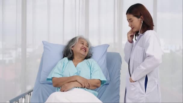 中型ショット アジアの高齢女性患者が胸部疾患のために入院した 女性の医師は肺呼吸をチェックするためにステートスコープを使用します 医療に関するコンセプト — ストック動画