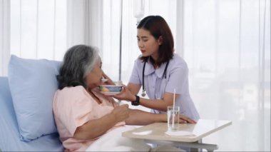 Elle yapılan iğne, yaşlı Asyalı hasta tedavi sırasında hastaneye yatırıldı. Hemşireler ona bakacak ve kendilerine bakamayacak durumdaki hastaları besleyecekti. Bir hemşire hastalarla ilgilenir.