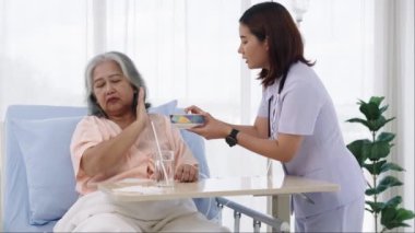 Elle yapılan iğne, yaşlı Asyalı hasta tedavi sırasında hastaneye yatırıldı. Hemşire bir hastaya bakıyor ve onu besliyor ama iştahsızlığı var. Hemşire, hastane ya da klinikte hastalara bakar.