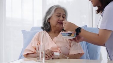 Elle yapılan iğne, yaşlı Asyalı hasta tedavi sırasında hastaneye yatırıldı. Hemşire bir hastaya bakıyor ve onu besliyor ama iştahsızlığı var. Hemşire, hastane ya da klinikte hastalara bakar.