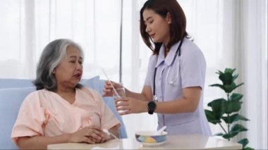 Elle yapılan iğne, yaşlı Asyalı hasta tedavi sırasında hastaneye yatırıldı. Hemşireler ona bakacak ve kendilerine bakamayacak durumdaki hastaları besleyecekti. Bir hemşire klinikte hastalarla ilgilenir..