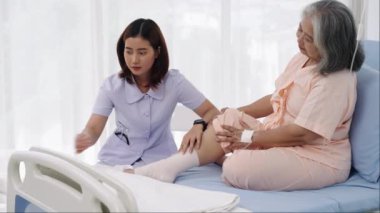 Elle yapılan iğne, yaşlı Asyalı bir hasta hastaneye yatırıldı. Bir hemşire yaralı bir hastanın bacağındaki bandajla ilgileniyor. Hemşire, hastane ya da klinikte hastalara bakar..