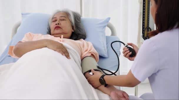 ハンドヘルドショット 高齢者の看護師または介護者は 患者の血圧と心拍数を測定する 病院やクリニックの患者さんのケア — ストック動画