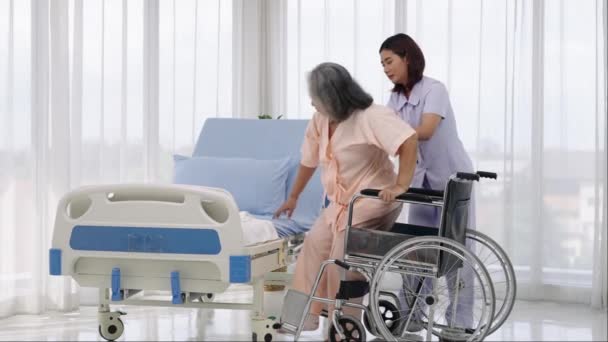 手持枪弹 一名护士将一名年迈的亚洲病人抬上轮椅 带他去拍摄他在车祸中受伤的腿的X光照片 护士在医院或诊所照顾病人 — 图库视频影像