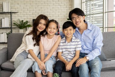 Mutlu aile ve yeni nesil oturma odasında. Kanepede oturan genç bir erkek ve kadın oğulları ve kızlarıyla birlikte mutlu bir şekilde vakit geçirir ve hatıra olarak aile fotoğrafları çekerler.