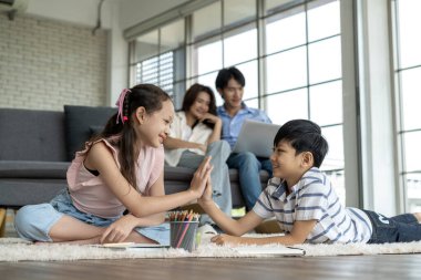 Kardeşler bir araya gelir ve çizimi tamamladıkları için onları tebrik ederler. Ebeveynler kanepedeki bilgisayarı kullanır. Çocuklar çizimi tamamladıkları için mutlular. Aile mutluluğu oturma odasında.