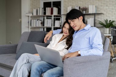 Mutlu aile oturma odasında. Genç bir çift dizüstü bilgisayarla kanepeye oturmayı planlıyor, ebeveynler kanepede dinleniyor ve bilgisayar hizmetlerini kullanarak aile hayatını planlıyorlar. 