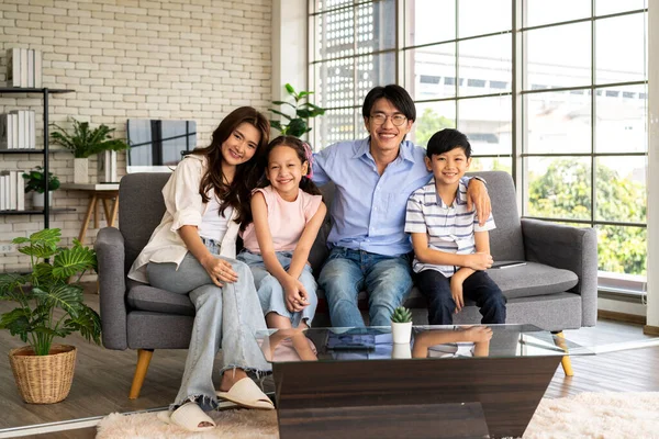 Happy family and the next generation in the living room. A young man and woman sitting on sofa with their son and daughter happily spend time together and take family photos as memories
