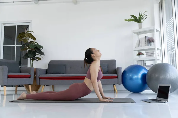 A woman practicing yoga at home for fitness and wellness. She is in a serene setting with her yoga mat and is focused on her breath. This image is perfect for fitness, wellness, and lifestyle content.