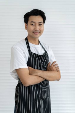 Genç ve yakışıklı bir barista gülümsüyor ve beyaz tişört ve önlük giyerek tezgah kuruyor. Moda ve şık bir kafede çalışıyor. Lezzetli kahve servisi yapıyor..