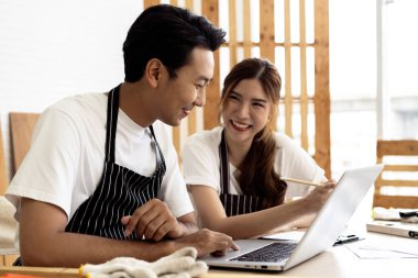 İki kahve dükkanı sahibi, bir dizüstü bilgisayarla dükkanlarının planlarını tartışarak bir yenileme projesinde işbirliği yapıyorlar.. 