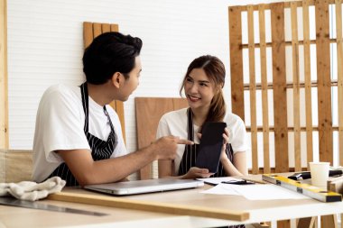 İki kahve dükkanı sahibi, bir dizüstü bilgisayarla dükkanlarının planlarını tartışarak bir yenileme projesinde işbirliği yapıyorlar.. 