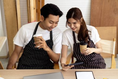 İki kahve dükkanı sahibi, bir dizüstü bilgisayarla dükkanlarının planlarını tartışarak bir yenileme projesinde işbirliği yapıyorlar.. 