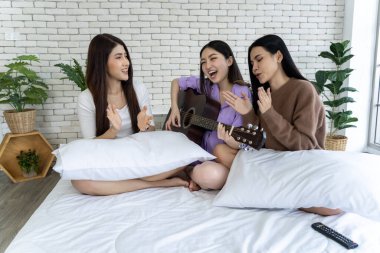 Bir grup mutlu arkadaş bir yatakta şarkı söylüyor ve gitar çalıyorlar. Çok eğleniyorlar ve müzik odayı neşeyle dolduruyor..