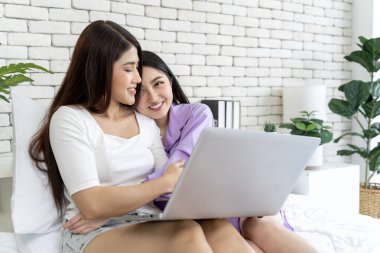 Genç bir LGBTQ çifti yatak odalarında boş vakitlerinde bilgisayar oyunları oynarken yan yana oturup birbirlerine sıkıca sarılırken gizli bir görüntü..