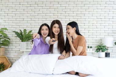 Rahatlama eğlenceyle tanışır, üç kadın bir yatakta uzaktan kumandayla TV dizisine daldırılır. Bu büyüleyici fotoğrafta arkadaşlığın, kahkahanın ve sohbetin tadını çıkarın.