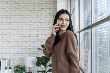 Teknik bağlantı, genç Asyalı kadın büyük cam bir duvarın yanında cep telefonu kullanıyor. Çağdaş yaşamın bu kentsel görüntüsündeki modern zarafeti ve bağlantıyı keşfedin