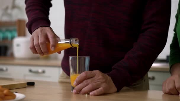 Handheld Locked Shot Close Hands Mature Husband Pouring Orange Juice — Stock Video