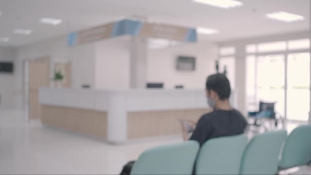 闭锁射击 医院或诊所走廊背景模糊 入口附近的柜台信息 病人坐在有清洁消毒环境的考场候诊区的椅子上 — 图库视频影像