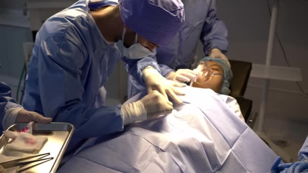 手持式头角枪法 专业外科医生小组在手术室对床上麻醉的女病人实施手术 由年轻的男性助手和护士移交工具 — 图库视频影像