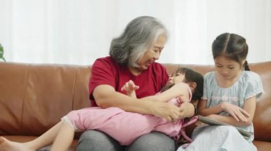 El kamerası görüntüsü, kanepede oturan büyük anne oturma odasında tabletle oynayan büyük kız torununun yanında çilek yiyip oynaşan küçük kız.