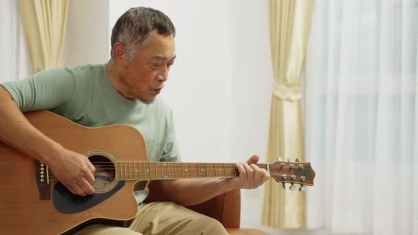 Filmación Cerca Hombre Retirado Sentado Sofá Tocando Guitarra Acústica Cantando — Vídeos de Stock