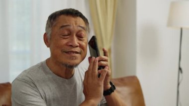 Görüntüler el kamerasıyla çekildi. Görme yetisini kaybeden Asyalı olgun bir adam cep telefonunun ekranını ses dinlemek için kaydırıyordu. Oturma odasında mutlu bir şekilde gülümsedi ve güldü..