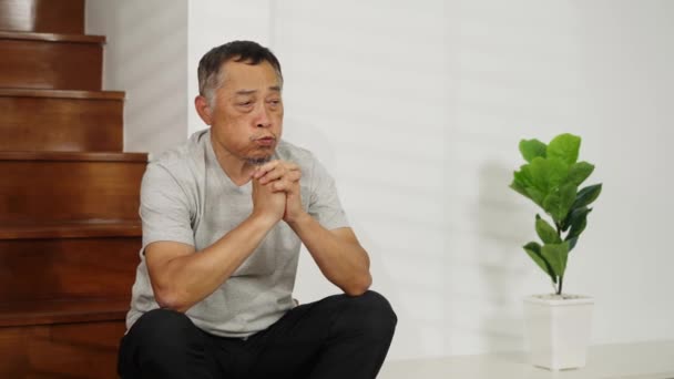 フッテージハンドヘルドミディアショット アジアの引退した男は 自宅の階段で考えるストレスで座って 彼は不安の表現を持っており 懸命に熟考する必要があります — ストック動画
