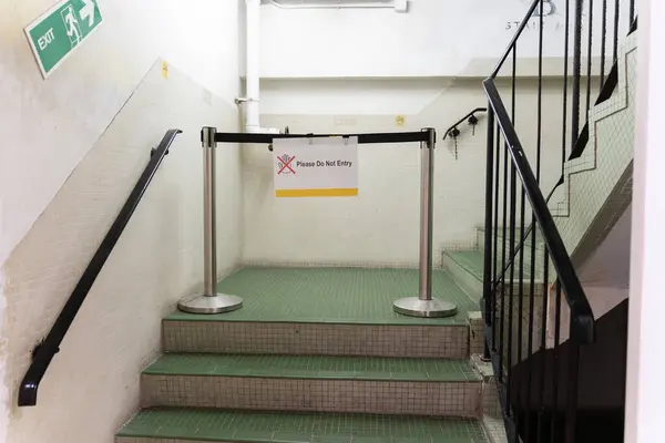 The rope barrier on staircase with railing, Emergency exit sign and warning sign do not entry