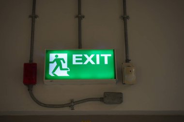 Çıkış tabelasında binanın duvarında ışık var, Banner kaçış kapısının üzerinde açıkça görünen bir acil çıkış tabelası var.
