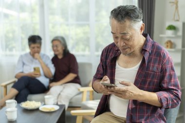 Seçici odaklanma, Asyalı son sınıf öğrencisi cep telefonu kullanarak iki bayan arkadaş mutlu bir şekilde konuşuyor ve gülüyorlardı. emeklilik grup toplantısı evde