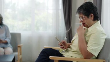 Orta yaşlı gözlüklü bir kadının el kamerası kaygılı bir şekilde telefonuna bakıyor, muhtemelen hisse senedi fiyatlarını ya da yatırım bilgilerini kontrol ediyor.