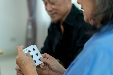 Seçici odaklanma, yakın plan çekimde elinde iskambil kağıtlarıyla şanslı bir eli gösteriyor. Bulanık arka planda bir insan var. Son sınıf arkadaşları oturma odasında kart oynamanın keyfini çıkarıyorlar.