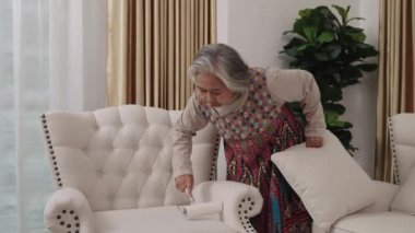 El kamerası görüntüsü, renkli elbiseli hizmetçi oturma odasındaki beyaz koltuğu temizlemek için pamuk rulo kullanıyor, temiz kalmasını sağlıyor..